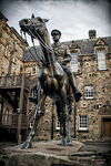 Estatua urbana en Edimburgo frente a edificios históricos de piedra.