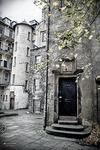 Callejón empedrado de Edimburgo con edificios antiguos y pequeña garita oscura.