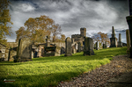 Ruinas y lápidas antiguas en un cementerio escocés con césped verde.