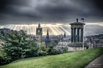 Vista de Edimburgo desde Calton Hill con monumentos clásicos y cielo tormentoso.