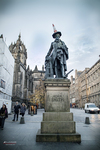 Estatua en Edimburgo frente a edificios históricos y arquitectura monumental.