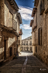 Calle estrecha de Pedraza con balcones de madera y casas de piedra.