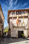Casa tradicional de Pedraza con balconada de madera y banderas en la fachada.