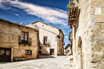 Calle luminosa de Pedraza con casas de piedra y suelo empedrado.