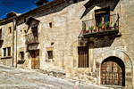 Fachada de casa señorial de piedra en Pedraza con balcones y macetas.
