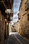 Callejón sombrío de Pedraza con balcones y muros de piedra.