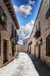 Calle tradicional de Pedraza con balcones, portones y cielo azul.