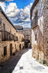 Calle curva de Pedraza con casas de piedra y suelo claro.