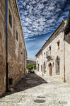 Calle tranquila de Pedraza con casa clara y cielo lleno de nubes.