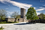 Torre de piedra en Pedraza junto a un árbol y una plaza vacía.