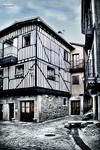 Rincón urbano de La Alberca con casa de madera, piedra y calle estrecha.