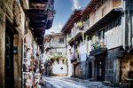 Calle luminosa de La Alberca con fachadas serranas y balcones floridos.