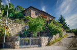 Calle en cuesta de Mogarraz con muros de piedra, jardines y arquitectura tradicional.