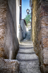 Pasadizo estrecho de piedra en Mogarraz con escaleras y luz al fondo.