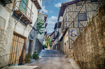 Calle empedrada de Mogarraz con fachadas de madera, piedra y cielo azul.