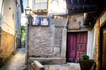 Rincón antiguo de Mogarraz con puerta de madera, piedra y retratos en la pared.