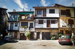Plaza o calle de Mogarraz con casas blancas, balcones de madera y coches aparcados.