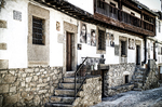 Casas blancas de Mogarraz con base de piedra, escaleras y balcones tradicionales.