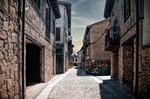 Calle estrecha del casco antiguo de Sequeros entre fachadas de piedra y casas rurales.
