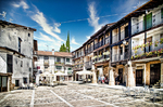 Plaza Mayor de Sequeros con soportales, casas tradicionales y cielo azul.