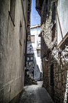 Callejón muy estrecho de Sequeros entre muros altos de piedra y yeso.