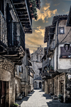 Calle antigua de Sequeros con fachadas tradicionales y cielo dramático al atardecer.