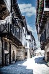 Calle soleada de Sequeros con soportales, balcones y casas tradicionales.
