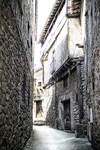 Callejón estrecho de Sequeros entre una fachada blanca y un muro de piedra.