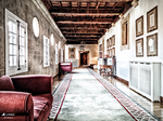 Galería interior con sillones rojos, ventanas y vigas antiguas en Monforte de Lemos.