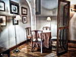 Rincón interior con mesa, sillas y cuadros en una estancia histórica de Monforte de Lemos.