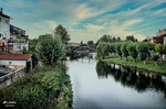 Paseo junto al río con vegetación y casas al fondo en Monforte de Lemos.