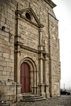 Fachada de iglesia con puerta roja y piedra tallada en Monforte de Lemos.