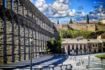 Vista del Acueducto de Segovia cruzando la plaza con cielo azul.