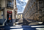 Calle estrecha entre edificios antiguos y el Acueducto de Segovia.