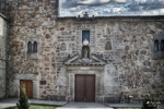 Fachada sobria de piedra con puerta central en Ávila.