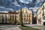 Plaza histórica de Ávila con edificios tradicionales bajo cielo dramático.