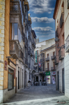 Calle estrecha del casco antiguo de Ávila con fachadas de colores.