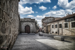 Rincón urbano con arco y edificios antiguos junto a la muralla de Ávila.
