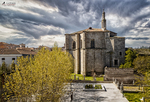 Iglesia de piedra junto a la muralla de Ávila bajo cielo nublado.