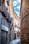 Calle comercial estrecha entre edificios históricos de Toledo.