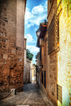 Callejón luminoso entre muros antiguos en el centro histórico de Toledo.