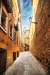 Calle curva empedrada entre edificios antiguos del casco histórico de Toledo.