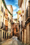 Calle estrecha con fachadas de colores en el centro de Toledo.
