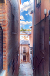 Paso estrecho entre muros altos en una calle antigua de Toledo.