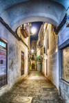 Callejón nocturno iluminado con bóveda azulada en el casco histórico de Cáceres.