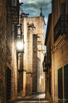 Calle estrecha iluminada de noche entre edificios históricos de Cáceres.