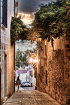 Calle estrecha con terraza al fondo y luz de atardecer en Cáceres.