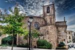 Iglesia de piedra con árboles en una plaza antigua de Cáceres.