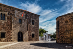 Plaza de piedra con edificios históricos y ábside circular en Cáceres.