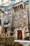 Fachada de palacio de piedra con balcón histórico en Cáceres.